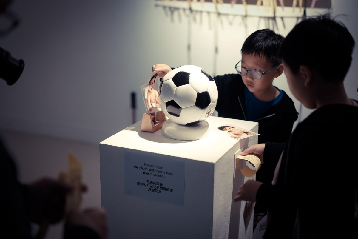 Visitors using a football and baby photograph to generate a printed fortune