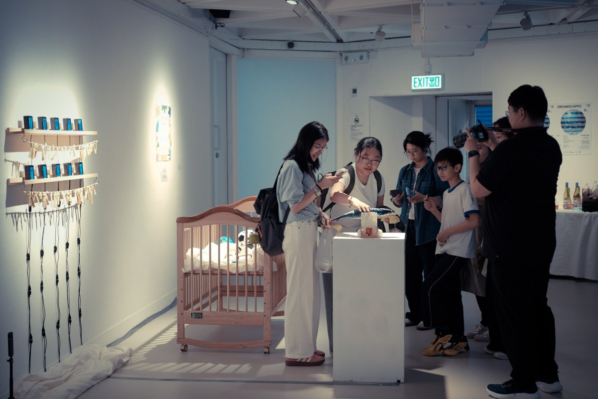 Visitors exploring Cradle of Success beside the cradle and wall of video displays